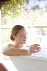 Woman having champagne in bubble bath