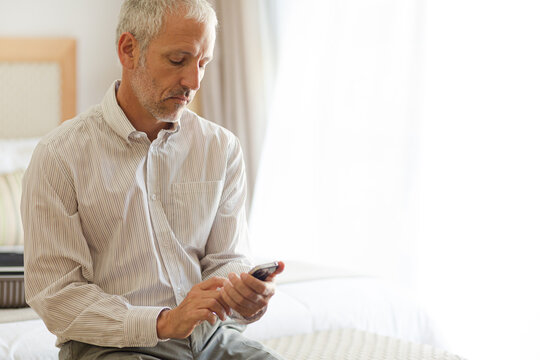 Businessman using cell phone in hotel room
