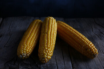 fresh corn cobs on a textured table made of old wood