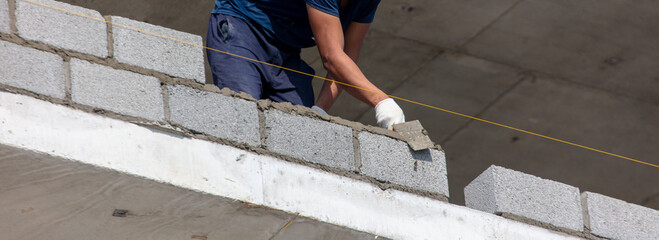A worker lays bricks on a wall