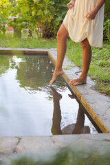 Woman dipping feet in pond