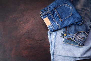 Blue jeans laying on a dark wooden table. Modern fashion jeans - top view with space to copy text.