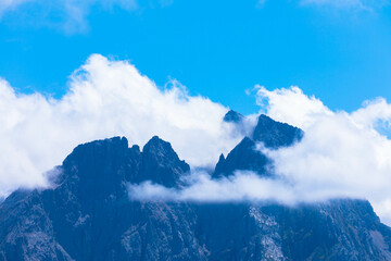 Rocky peak of Zugspitze through fluffy clouds and fog. Place for text.