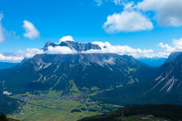 Tyrolean Zugspitze Arena. Panoramic aerial view at the Zugspitze mountain with a big cumulus cloud. The highest mountain in Germany. Seen from Lermoos village. Tourism and vacations concept.