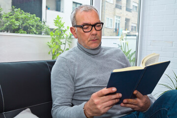mature man reading on the sofa at home