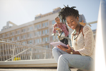 Woman using digital tablet on city street