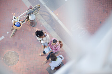 Friends using digital tablet on city street