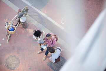 Friends using digital tablet on city street