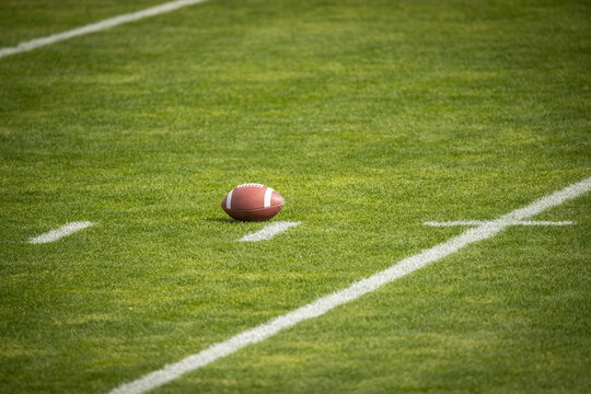 American Football field. Grass field with a football resting on the yard marker. Lots of copy space.