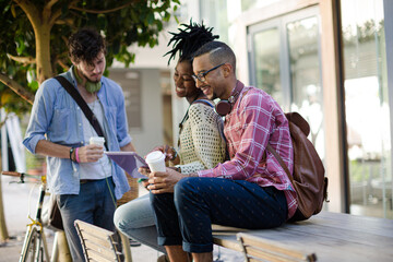 Friends using digital tablet on city street