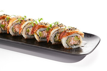 International sushi roll topped with smoked eel and sesame seed. Sushi roll with avocado and crab meat inside. Black slate sushi plate isolated on white background. Delicious sushi restaurant menu.