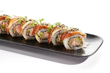 Fotobehang International sushi roll topped with smoked eel and sesame seed. Sushi roll with avocado and crab meat inside. Black slate sushi plate isolated on white background. Delicious sushi restaurant menu. © Ryzhkov