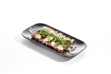Beef tataki - seared beef,. thinly sliced sashimi style. Beef tataki served with delicious ponzu tataki sauce. Japanese style meat on black plate isolated on white background..