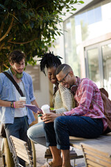 Friends using digital tablet on city street