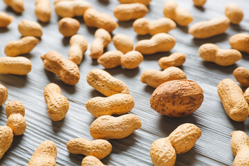 Nutmeg among peanuts on light wooden background. Concept of uniqueness