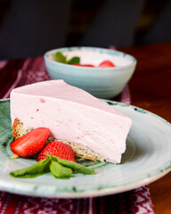 Freshly baked strawberry cheesecake with fresh strawberries and mint. Served on a plate.