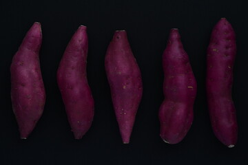 Sweet potatoes on black background.