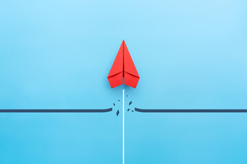 Red paper plane breaking through obstacle on blue background, Concept of overcoming barriers, goal,...