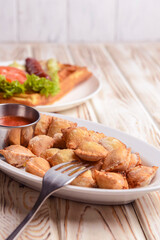 Fried dumplings stuffed with meat and served with tomato sauce on a white plate.