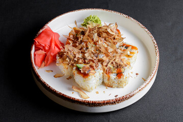 Tuna sushi in white dish served with wasabi sauce, pickled ginger. Over black background.