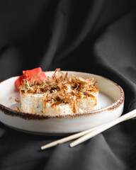 Tuna sushi in white dish served with wasabi sauce, pickled ginger. Over black background.