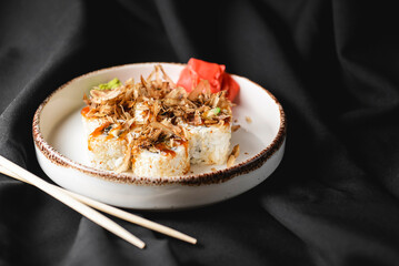 Tuna sushi in white dish served with wasabi sauce, pickled ginger. Over black background.