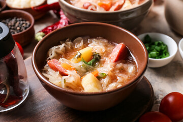 Bowls with tasty sauerkraut soup and ingredients on table