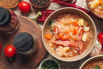 Bowl with tasty sauerkraut soup and ingredients on table