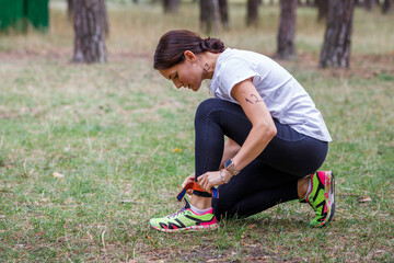 Young fitness woman fastens her participant chip before start of running race in the forest