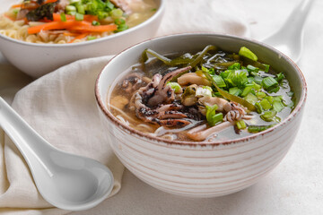 Tasty Chinese soup in bowl on light background