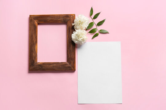 Composition with blank sheet of paper, empty picture frame and flowers on color background