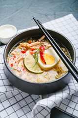 Bowl of tasty Thai soup with chicken on dark background