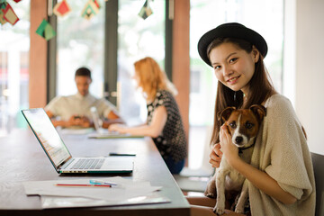 Woman holding dog and working in office
