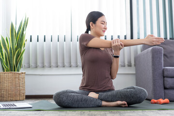 A smiling girl doing Deltoid Stretch for her shoulders exercising as her indoor leisure