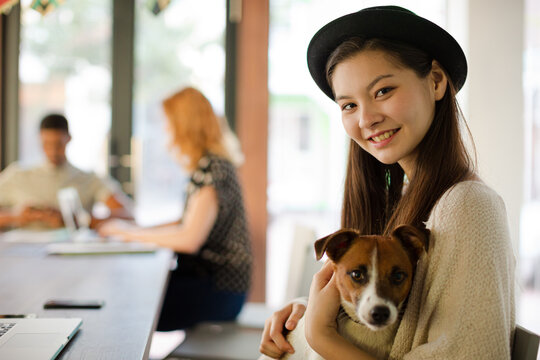 Woman holding dog and working in office