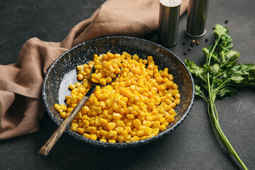 Bowl with corn kernels on dark background