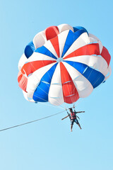 A man parasailing in the sky.  Colourful parachute in the sky. parasailing in Goa, India. Parasailing a water sport and a recreational sport.