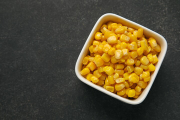 Bowl with corn kernels on dark background