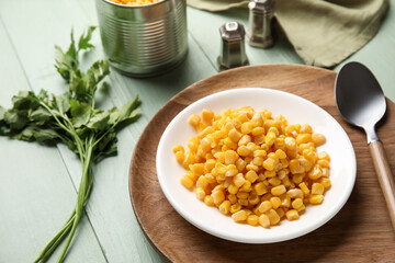 Plate with corn kernels on color wooden background