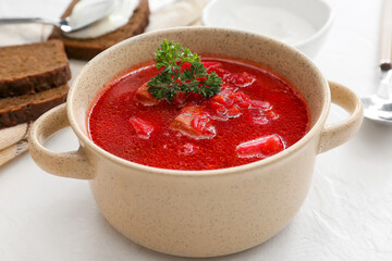 Pot with tasty borscht on light background