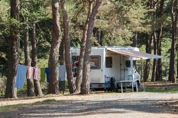 Camping-car installé à l'ombre sous les pins avec le linge qui sèche