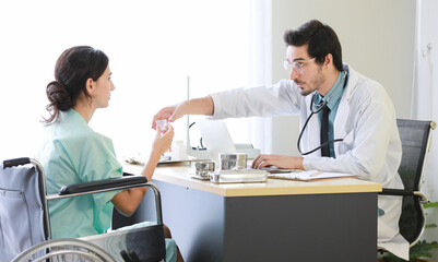 Obraz premium Doctor giving pills to female patient on wheelchair