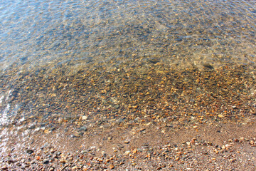 Close-up and top view of shiny transparent yellow sand and stones on the beach with clear water. clear sea, the river reveals the beauty of a natural resting place in the summer under the sun. Has a