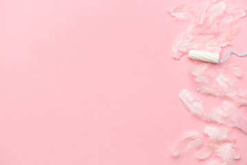 Tampon and feathers on color background