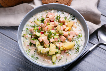 Bowl with tasty okroshka on dark wooden background