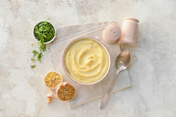Bowl of tasty mashed potatoes with garlic on light background