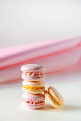 Colorful pastel french macaroons or macarons  on white and pink background