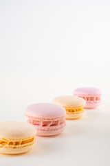 Fototapeta na wymiar Row of colorful pastel french macaroons or macarons on white and pink background