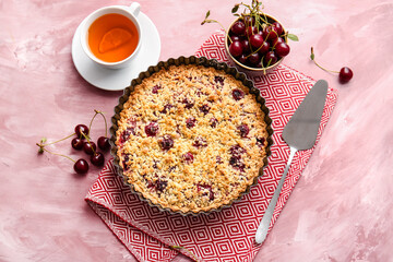 Baking dish with tasty cherry pie and cup of tea on color background