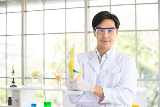 Image is Portrait. Asian man scientist or researcher wearing white coat and protective glassware holding Artificial bone for research in laboratory or hospital. Concept research bone human.
